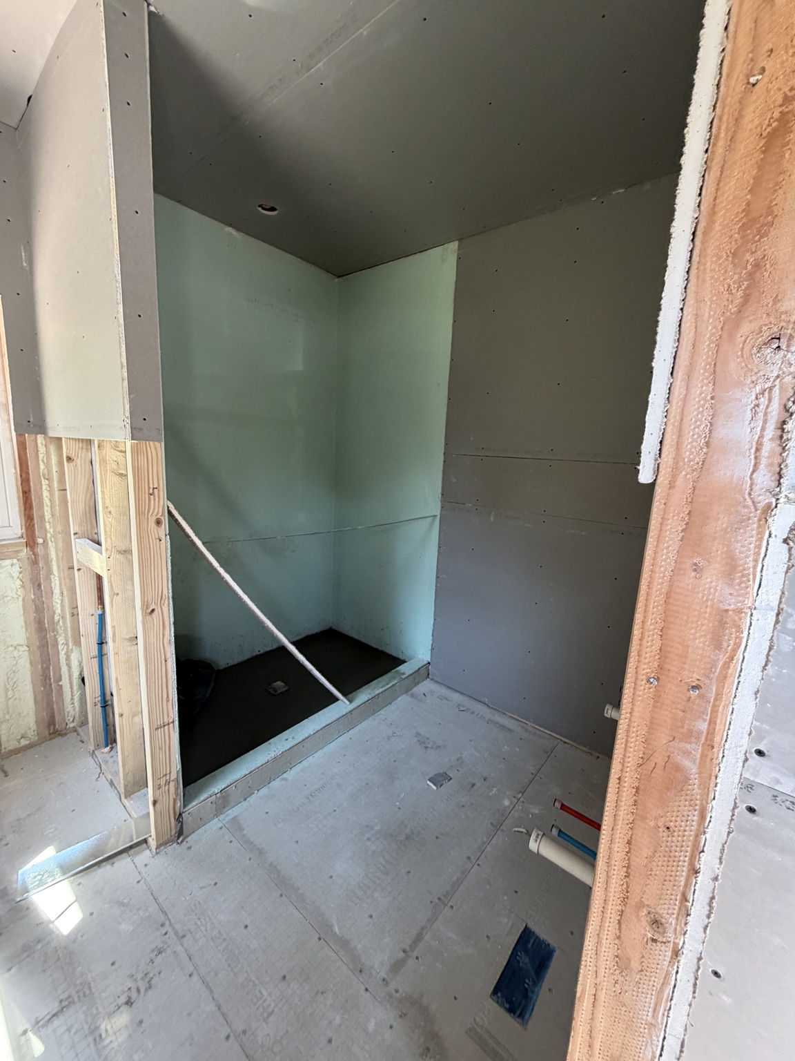 Bathroom and walk-in shower during drywall and waterproofing work